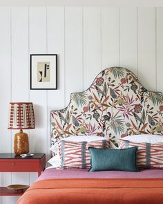 a bed with an upholstered headboard and colorful pillows on top of it