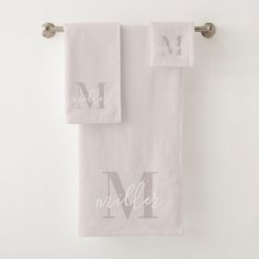 two white towels hanging on the wall with monogrammed letters in silver and white