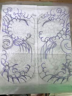 three drawings on paper with blue ink in the shape of flowers and swirls, one is