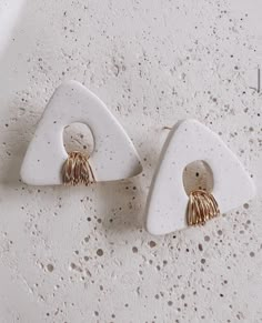 two pairs of white and gold earrings on top of a table with holes in the middle