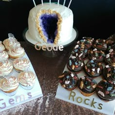 two cakes and cupcakes sitting on top of a table next to each other