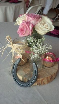 some flowers are sitting on top of a wooden block with a horseshoe and mason jar