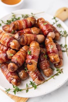 sausage wrapped in bacon and garnished with parsley on a white plate next to a cup of tea