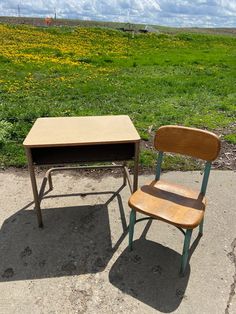 two school desks and a chair sitting on the ground in front of a field