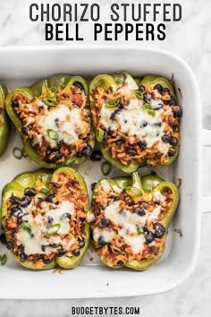 stuffed bell peppers in a white casserole dish with cheese and black olives