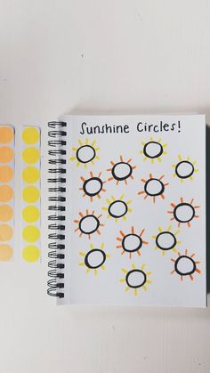 a spiral notebook with stickers on it next to an orange and yellow cupcake