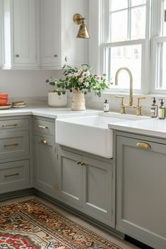 a white kitchen sink sitting under a window next to a potted plant on top of a counter