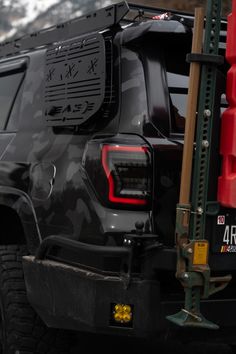 the back end of a black hummer truck parked in front of a mountain range