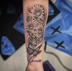 a woman's arm with butterflies and daisies on it that says besia