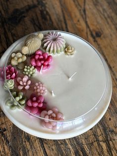 a white plate topped with lots of flowers on top of a wooden table next to a candle