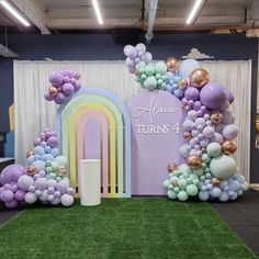 balloons and streamers decorate the backdrop for a birthday party in an office building with a rainbow arch