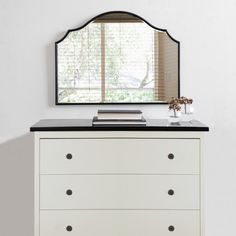 a white dresser with drawers and a mirror above it