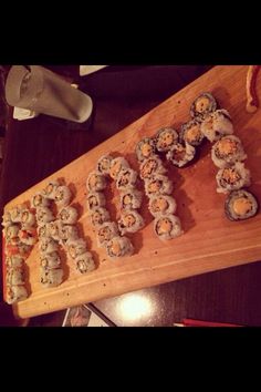 sushi rolls are arranged on a wooden cutting board