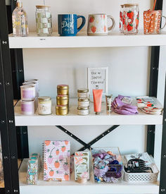 the shelves have many items on them and are decorated with flowers, candles, and greeting cards