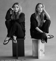 two women sitting on stools with their hands behind their heads, both looking at the camera