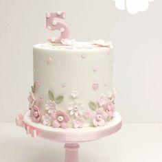 a white cake with pink flowers and the number five on top