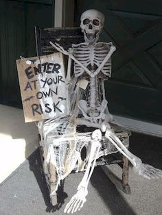 a skeleton sitting in a chair with a sign that says enter at your own risk