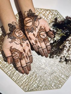 two hands with henna tattoos on them and some flowers in the backgrund