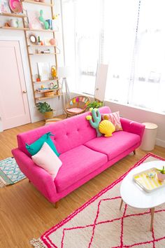 a living room with pink couches and colorful pillows