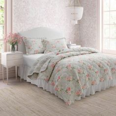 a white bed sitting next to a window in a room with pink flowers on it