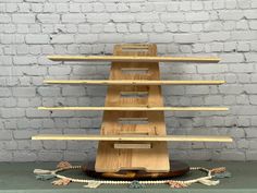 a wooden shelf sitting on top of a table next to a white brick wall,