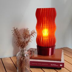 a red lamp sitting on top of a wooden table next to a vase with flowers