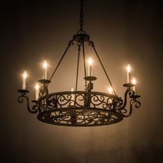 a chandelier with lit candles hanging from it's sides in a dark room