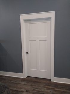 an empty room with a white door and wood floors