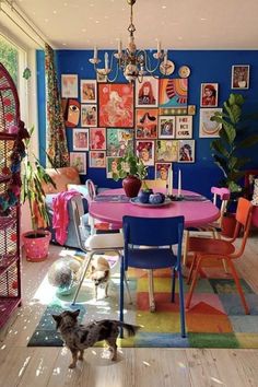 a colorful dining room with pictures on the wall and a dog standing in front of it