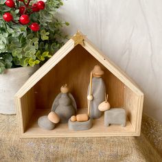 a small wooden nativity scene in front of a potted plant