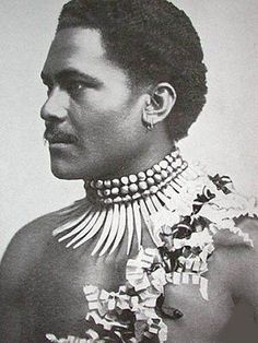 an old photo of a man with beads on his neck and chest, in black and white