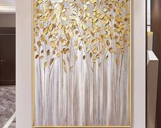 a painting hanging on the wall in a living room with white walls and gold accents