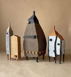 three small houses made out of cardboard are shown in front of a brown background and beige backdrop