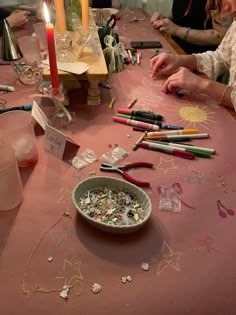 a group of people sitting around a table with some crafting supplies on top of it