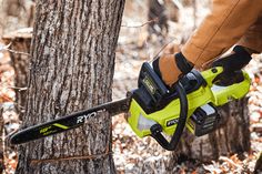 a man holding a chainsaw next to a tree