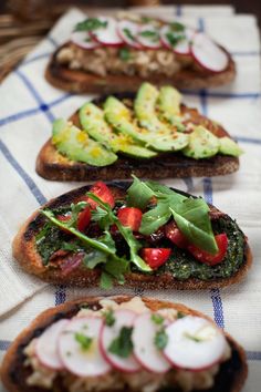 four slices of bread with veggies and other toppings on them sitting on a table