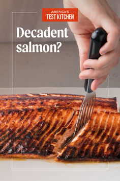 someone is cutting up a piece of salmon with a knife and fork