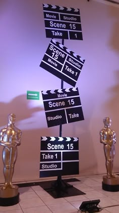 three oscar statues sitting on top of a white tiled floor in front of a movie sign