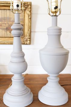 two white lamps sitting on top of a wooden table