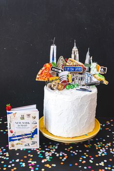 a white cake sitting on top of a yellow plate next to a book and confetti