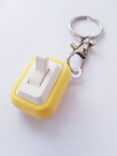 a yellow and white light switch sitting on top of a keychain