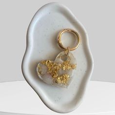 a white and gold heart shaped keychain on top of a white marble slab