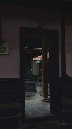 an open door leading into a dark room with columns and benches in the background at night