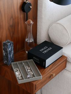 an open book sitting on top of a wooden table next to a vase and lamp