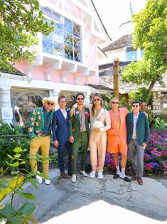 a group of people standing next to each other in front of some flowers and trees