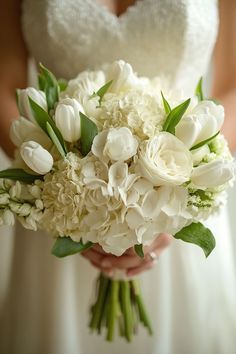 a bride holding a bouquet of white flowers