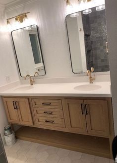 a bathroom with double sinks and two mirrors