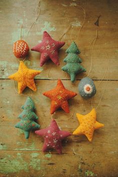 christmas ornaments made out of felt hanging from string on wooden surface with snowflakes and stars