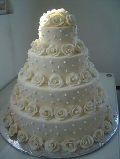 a three tiered wedding cake with white roses