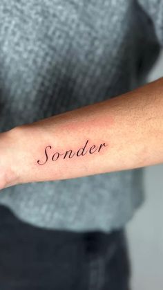 a woman's arm with the word sonder written in cursive font